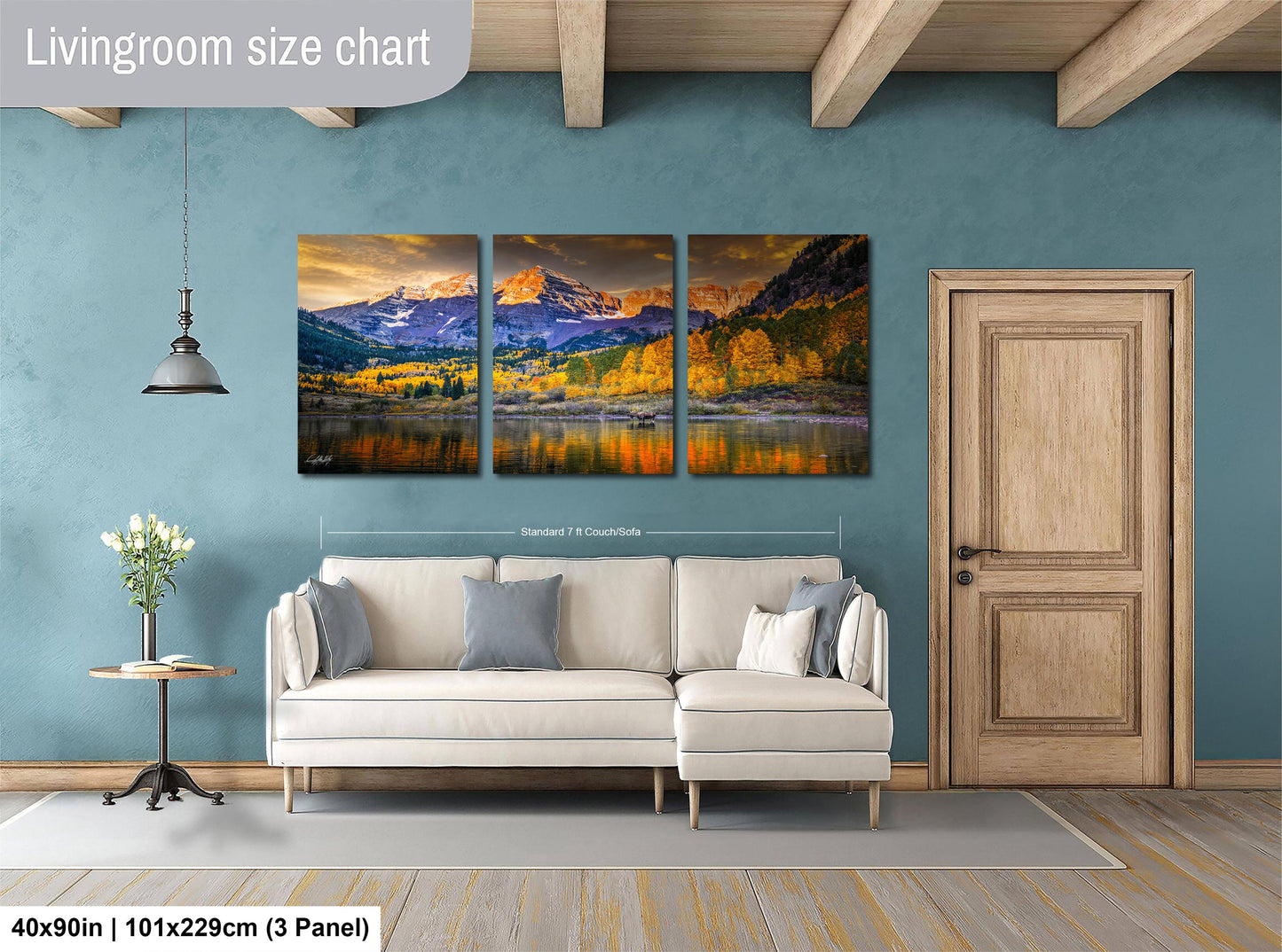 The image is a living room with a large, three-panel landscape painting hanging on the wall. The painting depicts a scenic mountain landscape with a lake and autumn foliage. The room has a white sofa and a wooden door, creating a cozy and inviting atmosphere.