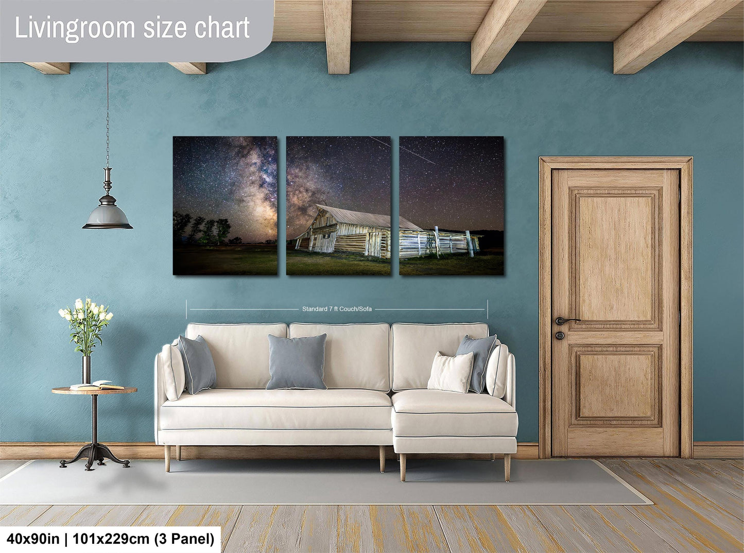 The image is a livingroom with a large white sofa, a wooden door, and a painting of a barn and starry sky hanging on the wall.