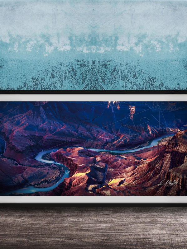 The image is a framed photograph of a breathtaking natural landscape, featuring a winding river surrounded by rugged mountains and valleys.