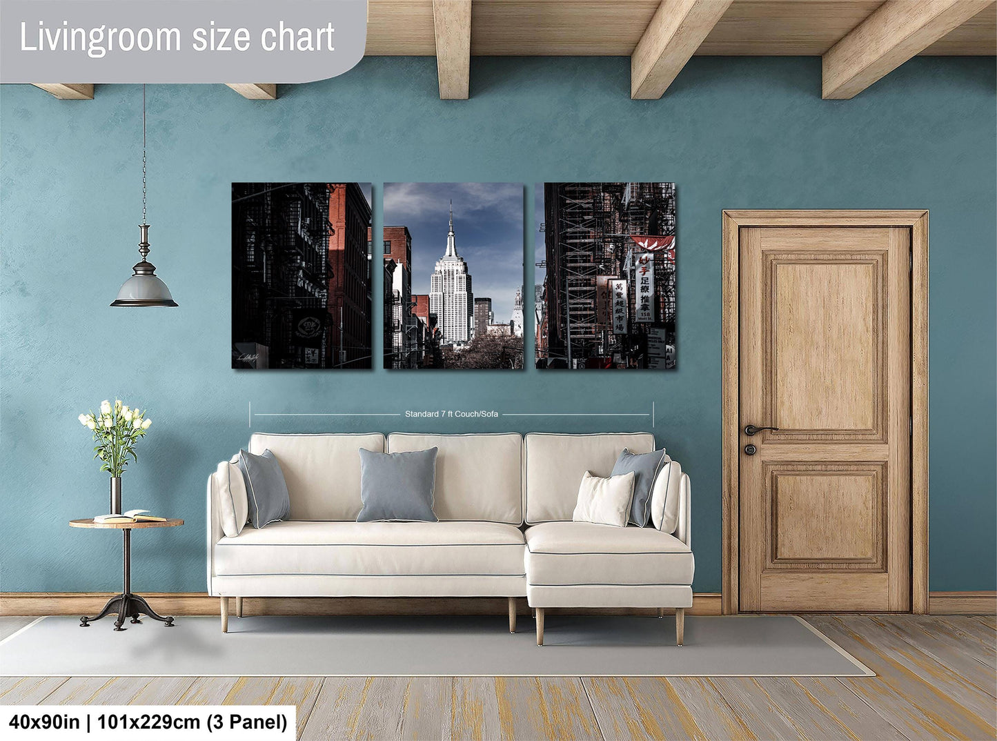 The image is a living room with a white sofa and a wooden door. Above the sofa, there is a livingroom size chart that provides dimensions for the artwork displayed on the wall. The artwork consists of three panels, each depicting a different cityscape, including the New York City skyline.