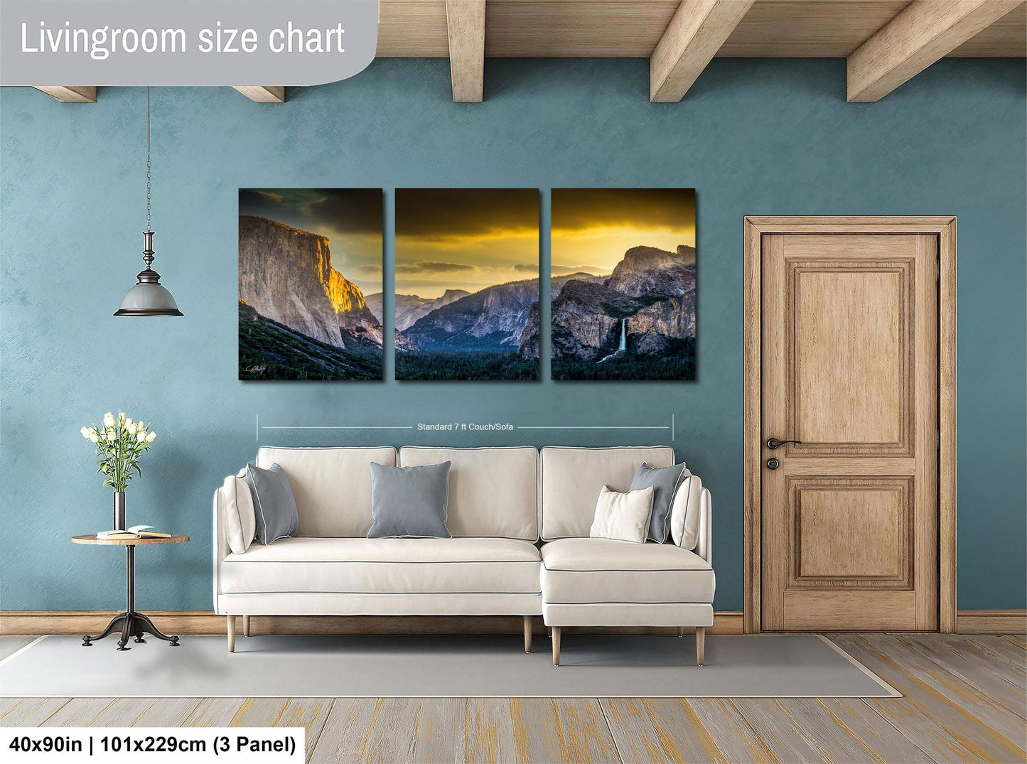 The image is a living room with a large wall art depicting a scenic mountain landscape. The wall art is divided into three panels, each showcasing a different part of the mountain range. The living room has a white sofa and a wooden door, creating a cozy and inviting atmosphere.