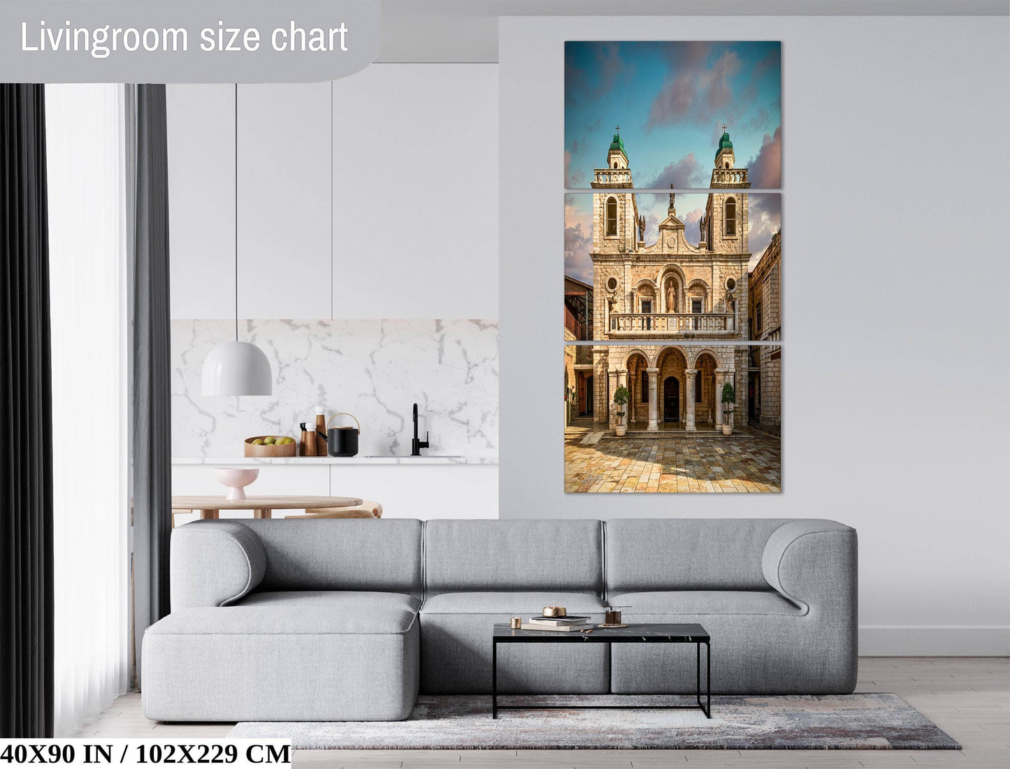 The image is a living room with a gray sofa and a coffee table. Above the sofa, there is a large painting of a building with two towers, which appears to be a church. The painting is mounted on the wall, and the living room has a modern and minimalist design.