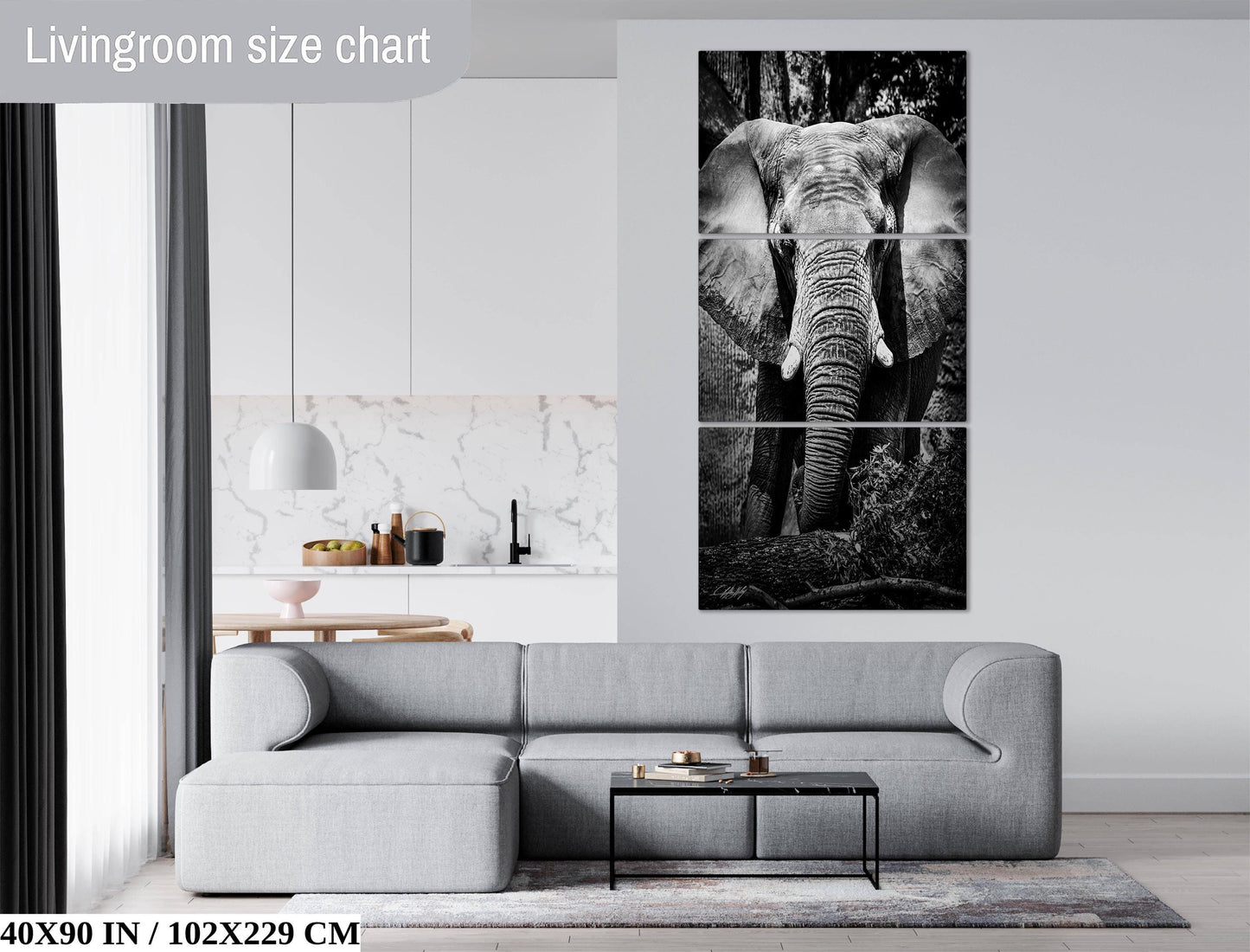 The image is a living room with a gray sofa, a coffee table, and a large black and white elephant painting on the wall.