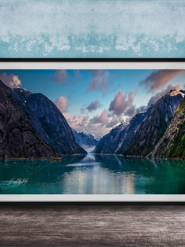 The image is a framed photograph of a serene mountain lake, with a stunning view of the mountains and the calm waters reflecting the sky.