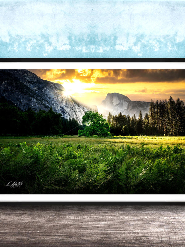 The image is a framed landscape photograph depicting a serene mountain scene with a lush green field, a tree, and a majestic mountain range in the background.