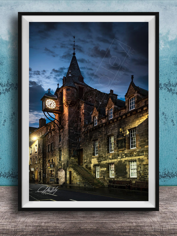 a historic stone building with a clock tower, set against a dark sky with clouds.