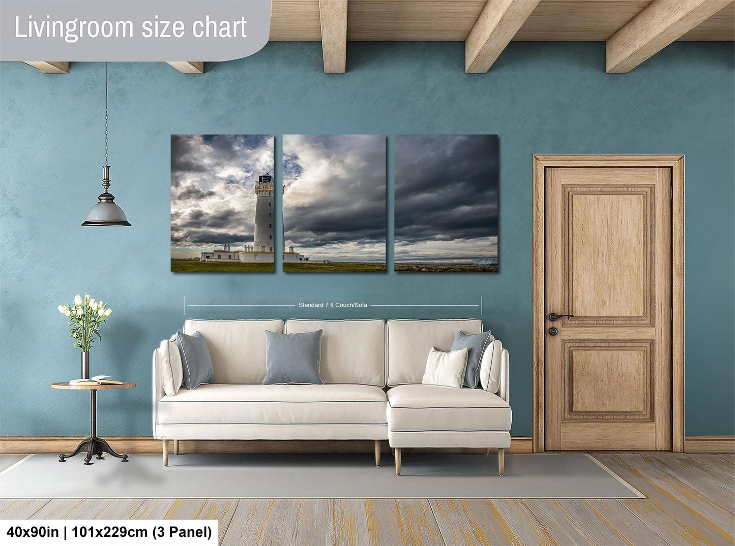 The image is a living room with a white sofa and a wooden door. Above the sofa, there is a large painting depicting a lighthouse and a cloudy sky. The painting is divided into three panels, with the largest panel covering the entire wall. The wall itself is painted in a light blue color. The sofa is positioned in front of the painting, creating a cozy and inviting atmosphere in the living room.