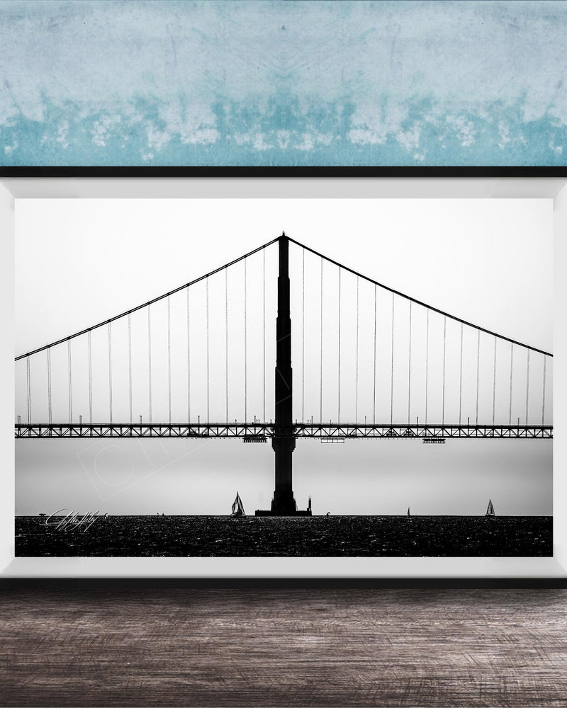 A black and white photograph of the Golden Gate Bridge in San Francisco, California, with a blue textured wall in the background.