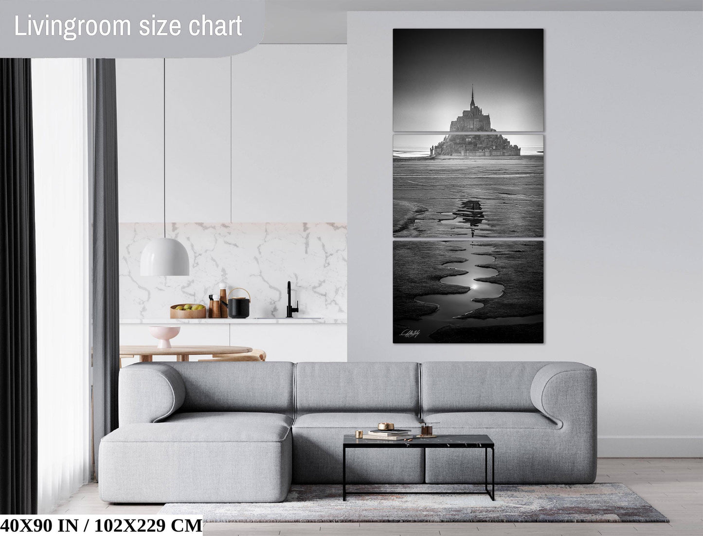 The image is a living room with a gray sofa, a coffee table, and a large black and white photograph of a castle or palace on the wall.