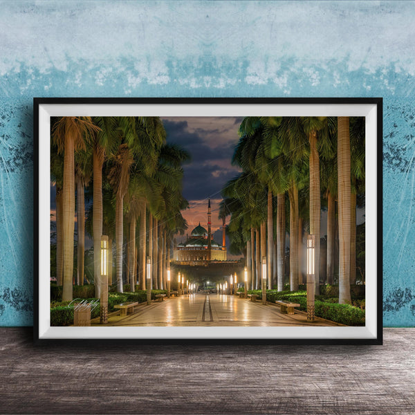 A framed photograph depicting a serene nighttime scene of a palm-lined walkway leading to a building, with the sky illuminated by the warm glow of the setting sun.