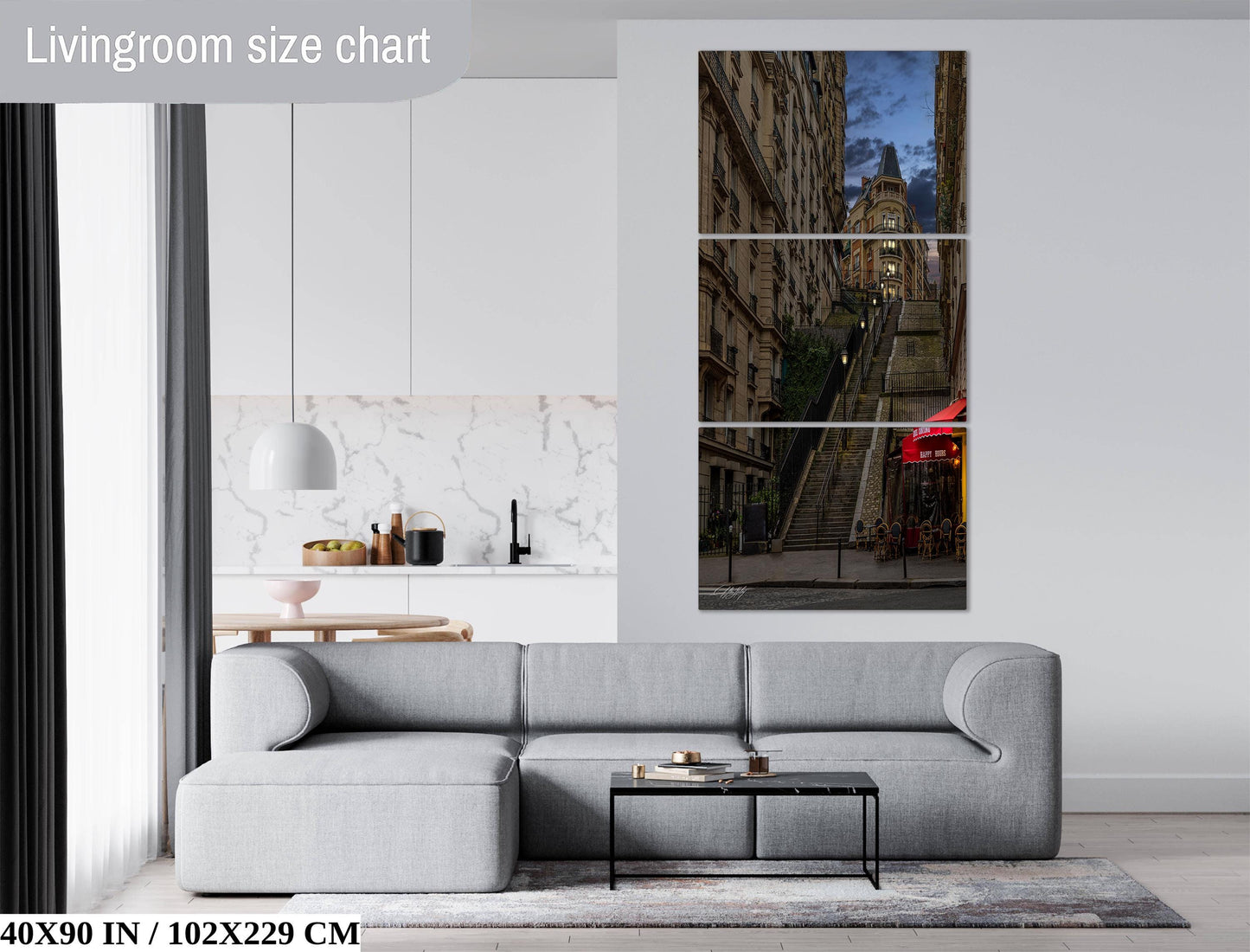 The image is a living room with a gray sofa, a coffee table, and a large wall art depicting a city street with tall buildings and a staircase.