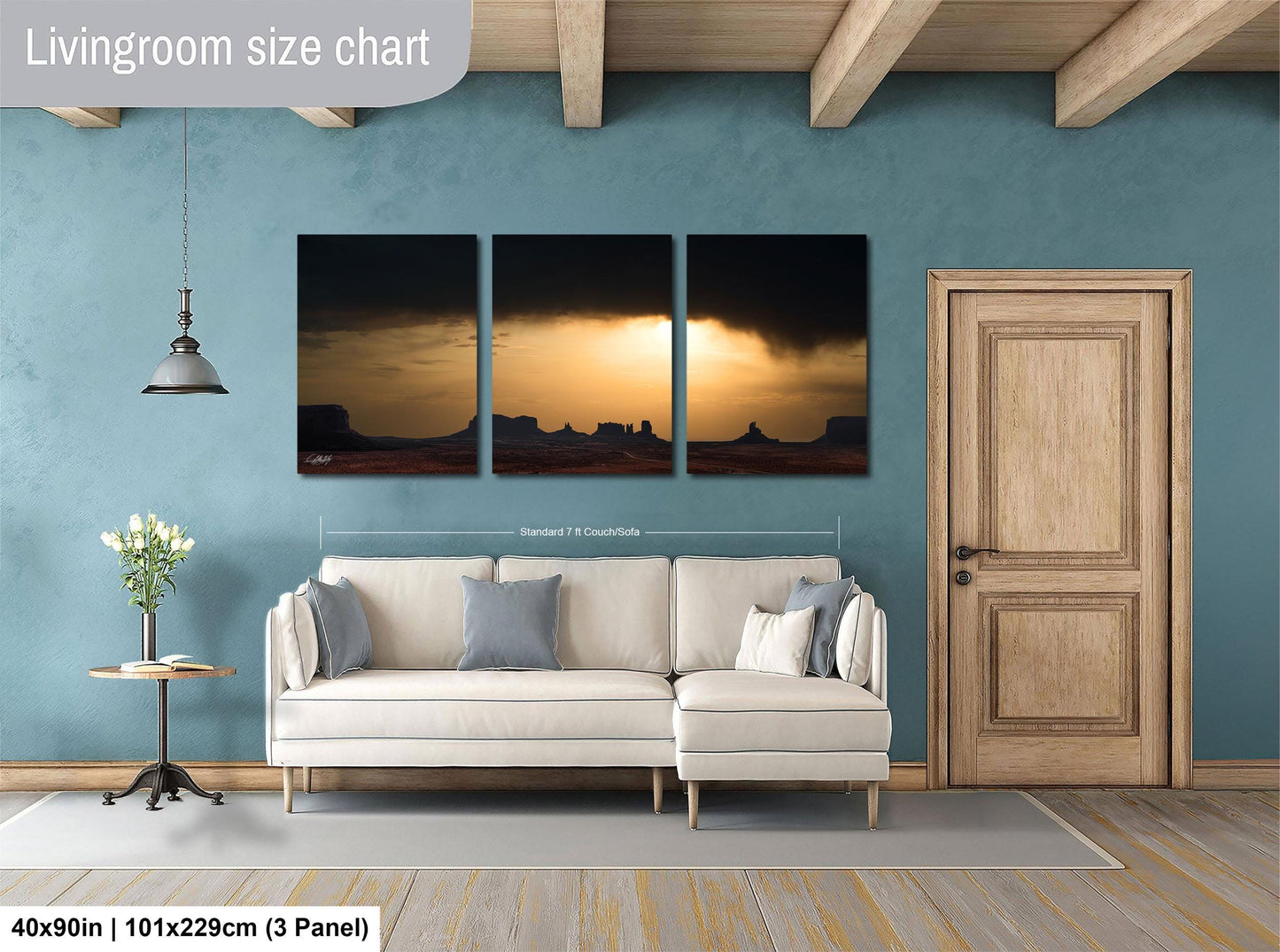 The image is a living room with a large living room size chart on the wall, a white sofa, a wooden door, and a small table with a vase of flowers.