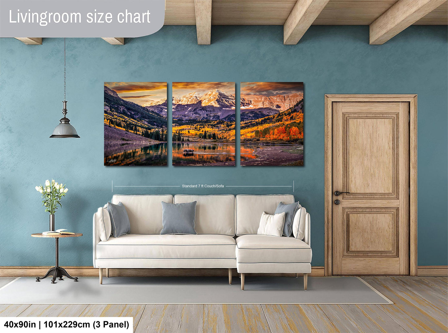 The image is a living room with a large, three-panel landscape painting hanging on the wall. The painting depicts a scenic mountain landscape with a lake and autumn foliage. The room has a white sofa and a wooden door, creating a cozy and inviting atmosphere.