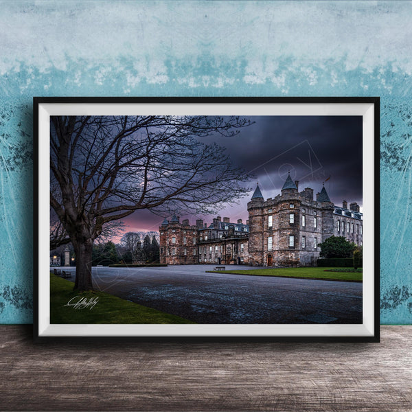 A framed photograph of a castle with a tree in the foreground, set against a dark, cloudy sky.
