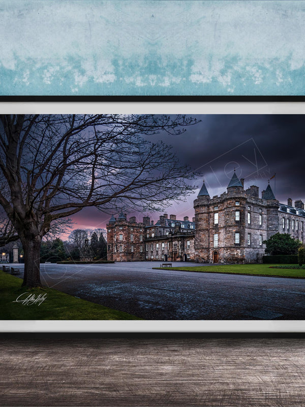 A framed photograph of a castle with a tree in the foreground, set against a dark, cloudy sky.