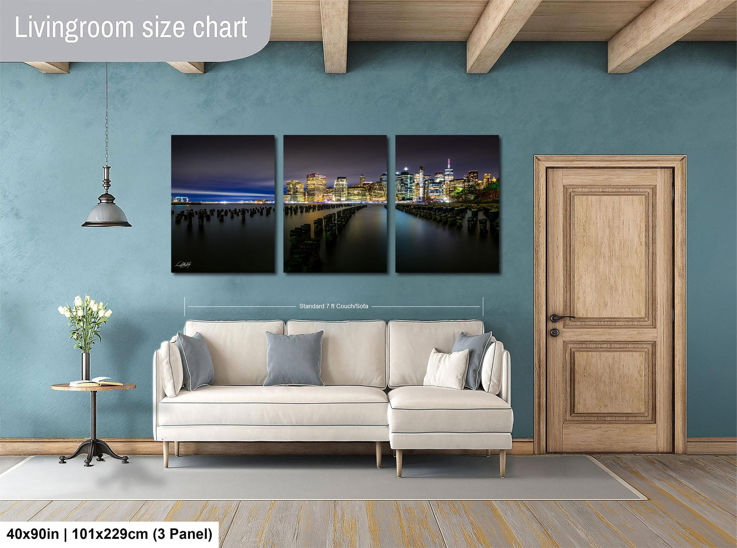 The image is a living room with a large white sofa and a wooden door. Above the sofa, there is a wall-mounted living room size chart that provides dimensions for the artwork displayed on the wall.