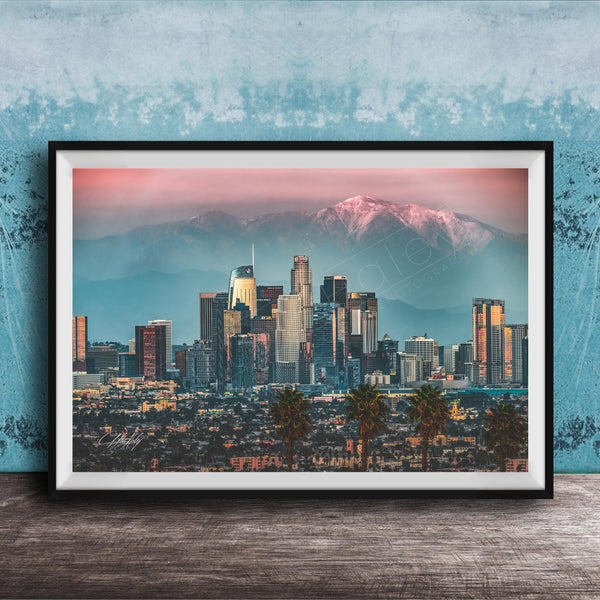 A framed photograph of the Los Angeles skyline at sunset, with the city's skyscrapers and mountains in the background.