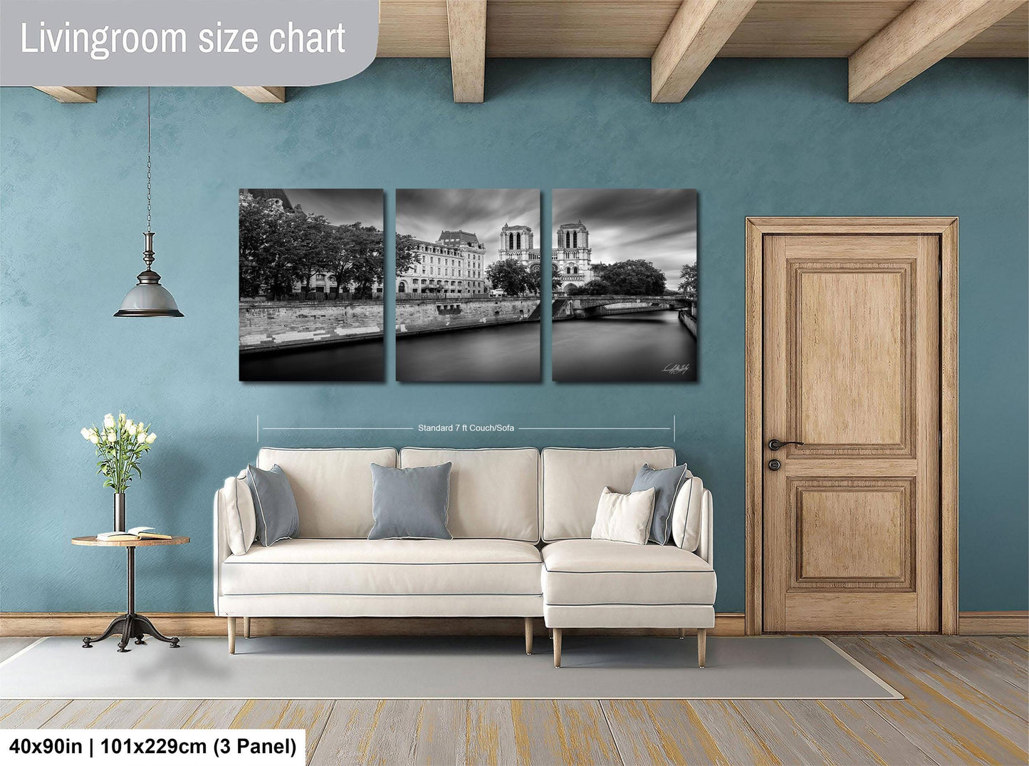 The image is a living room with a white sofa and a wooden door. Above the sofa, there is a triptych of black and white photographs depicting a cityscape with a river and buildings. The wall behind the sofa has a blue color, and there is a lamp hanging from the ceiling. The image is labeled as a "Livingroom size chart" and includes dimensions and a reference to a "3 Panel" format.