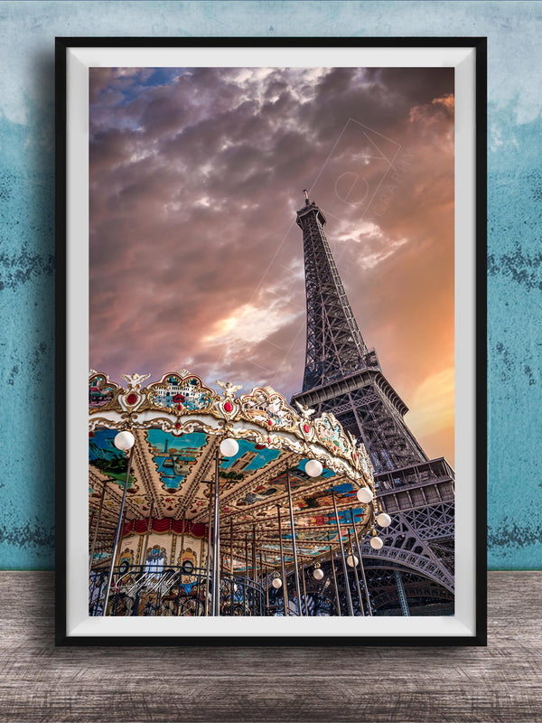 A framed photograph of the Eiffel Tower and a colorful carousel, set against a dramatic sky with clouds.