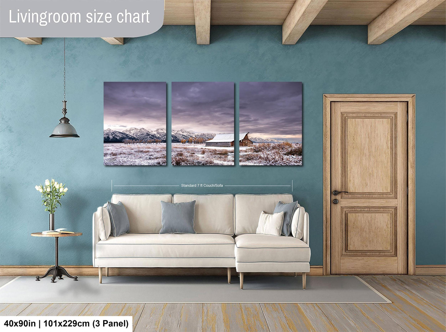 The image is a living room with a large, three-panel landscape painting hanging on the wall. The painting depicts a snowy mountain scene with a cabin in the distance. The room has a white sofa and a wooden door, creating a cozy and inviting atmosphere.
