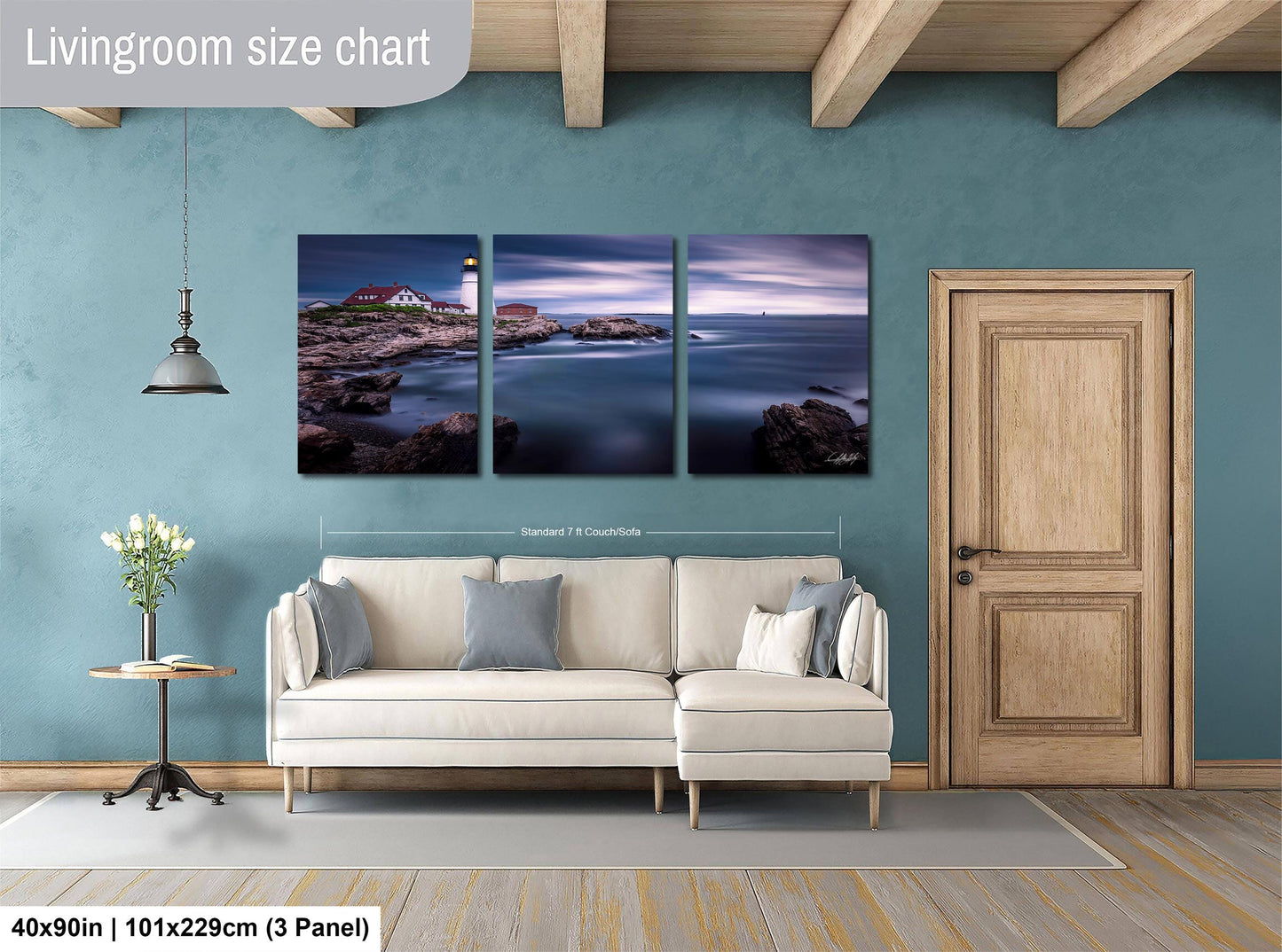 The image is a living room with a large, three-panel landscape painting hanging on the wall. The painting depicts a serene coastal scene with a lighthouse and the ocean. The room is furnished with a white sofa and a wooden door, creating a cozy and inviting atmosphere.