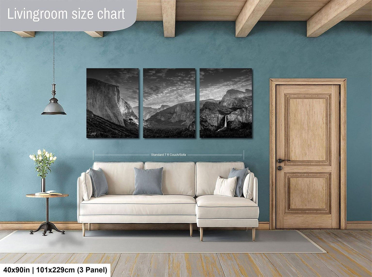 The image is a living room with a large wall art piece depicting a mountainous landscape. The living room has a white sofa and a wooden door, and the wall art is approximately 40 inches wide and 101.29 cm tall.