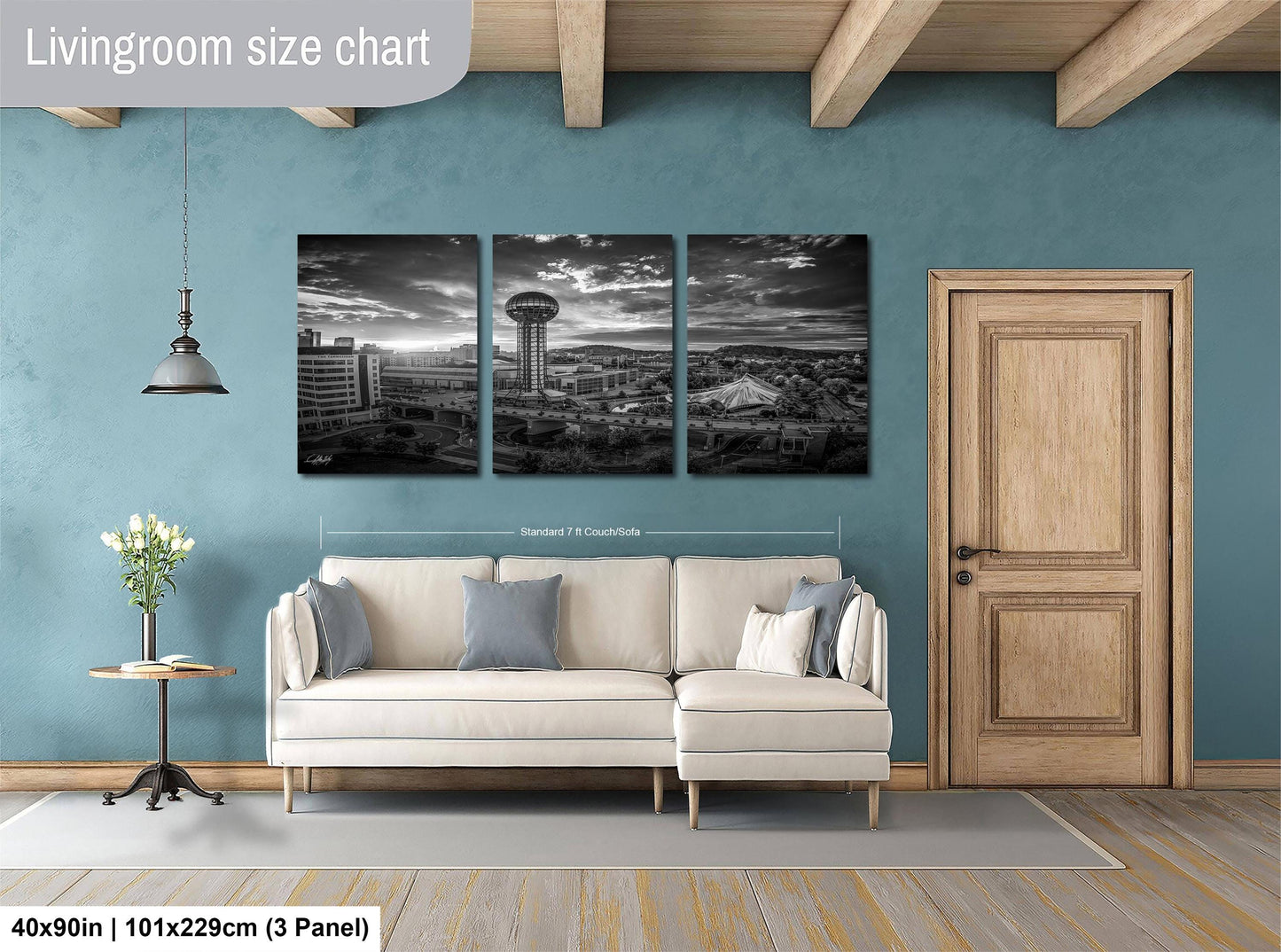 The image is a living room with a white sofa and a wooden door. Above the sofa, there is a large black and white photograph of a city skyline, which appears to be a triptych. The wall behind the sofa has a blue color, and there is a lamp hanging from the ceiling. The image is labeled as a "Livingroom size chart" and includes dimensions and a reference to a "3 Panel" format.