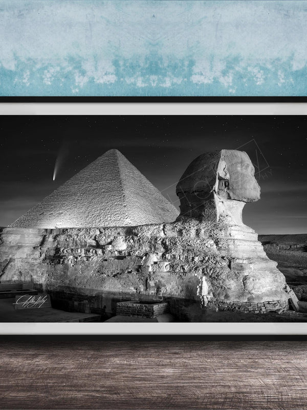 A black and white photograph of the Great Sphinx and the Pyramid of Giza against a night sky, with a small shooting star visible in the sky.