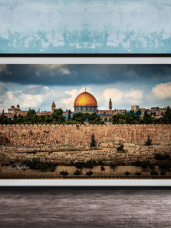 the Dome of the Rock, a significant landmark in Jerusalem, Israel. The photograph is framed and displayed on a wooden surface, showcasing the architectural beauty of the structure against a cloudy sky.