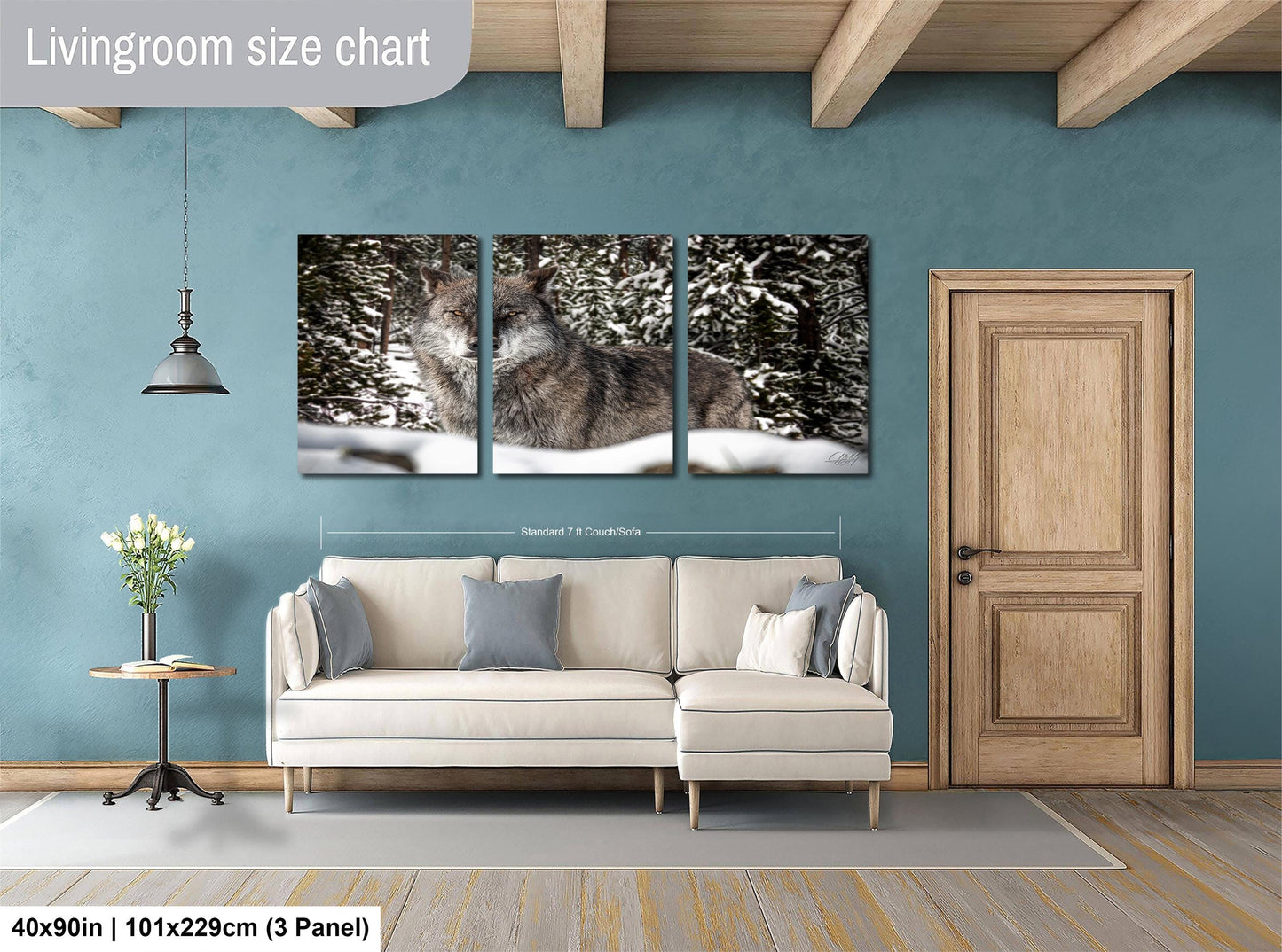 The image is a living room with a large living room size chart on the wall, featuring a three-panel print of a wolf in a snowy forest. The room has a white sofa, a wooden door, and a wooden floor.