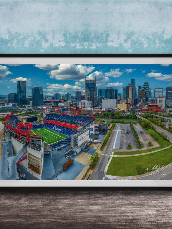 The image is an aerial view of a city skyline, featuring tall buildings and a large sports stadium with a red roof.