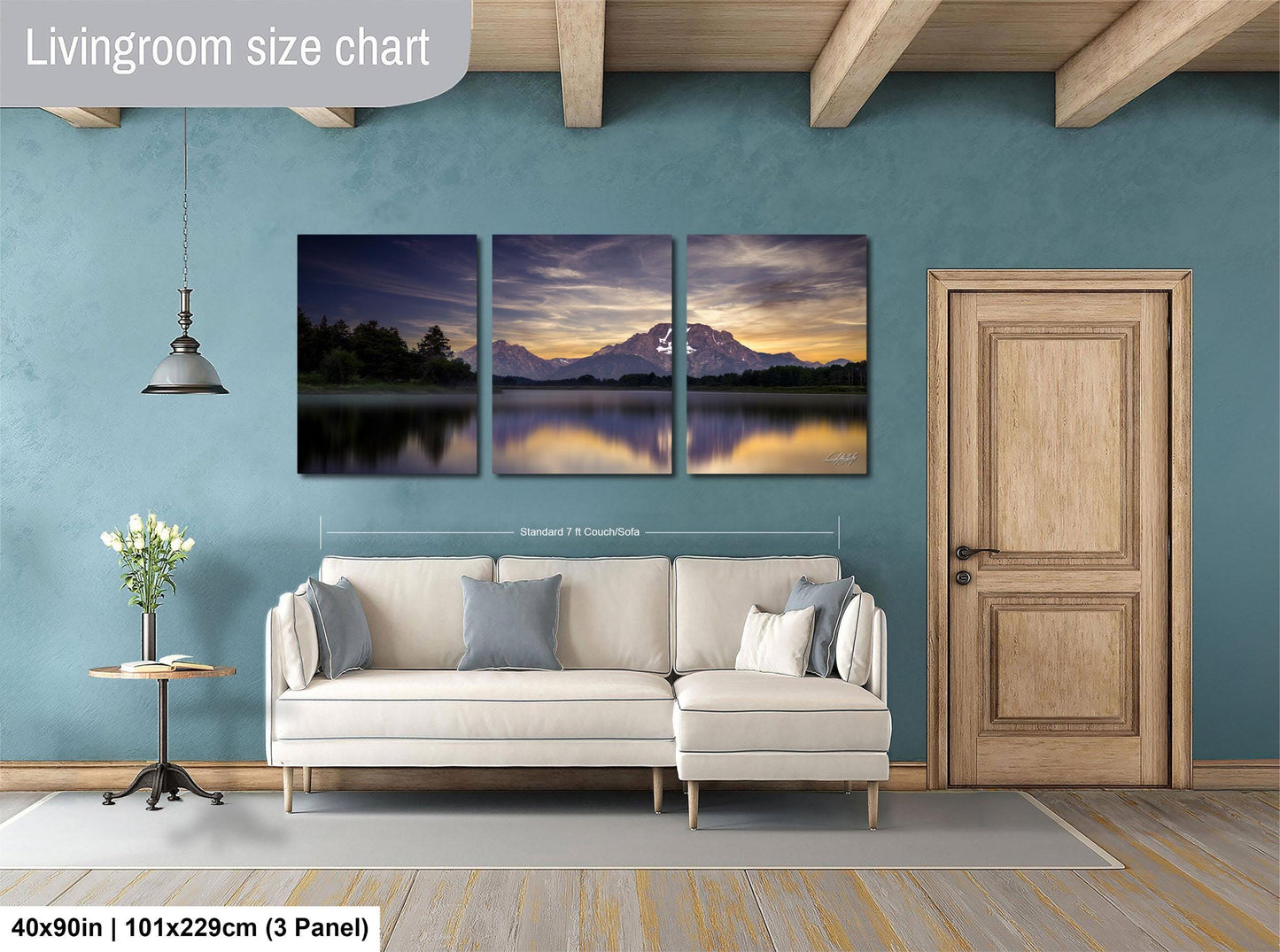 The image is a living room with a large wall art piece depicting a serene landscape with a mountain and a lake. The art piece is divided into three panels, each showcasing different aspects of the scene. The living room has a white sofa and a wooden door, creating a cozy and inviting atmosphere.