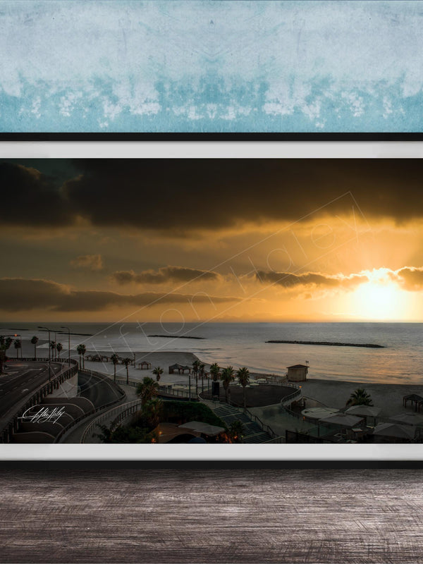 The image is a framed photograph of a beach at sunset, with palm trees and a body of water in the background.