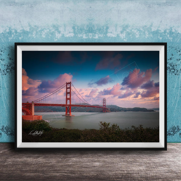 A framed photograph of the Golden Gate Bridge at sunset, with the bridge's distinctive red towers and suspension cables silhouetted against a colorful sky.