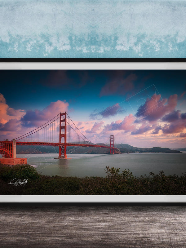 A framed photograph of the Golden Gate Bridge at sunset, with the bridge's distinctive red towers and suspension cables silhouetted against a colorful sky.