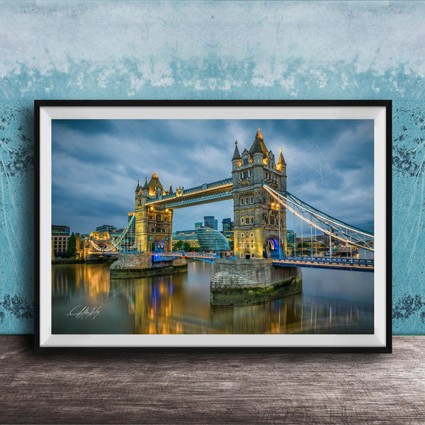 A framed photograph of the iconic Tower Bridge in London, England, illuminated at night against a cloudy sky.
