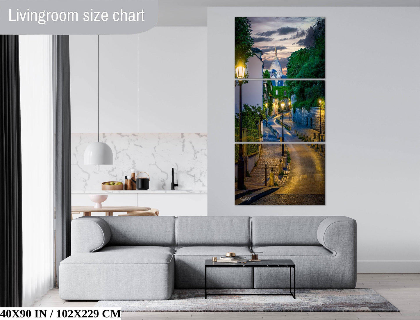 The image is a living room with a gray sofa, a coffee table, and a large wall art depicting a street scene with trees and lampposts.