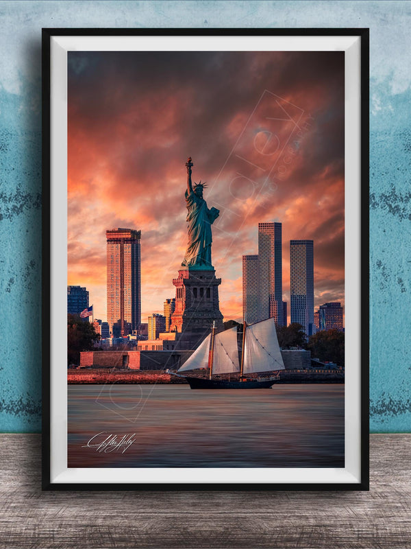a framed photograph of the Statue of Liberty in New York City, with the city skyline in the background and a sailboat in the foreground.