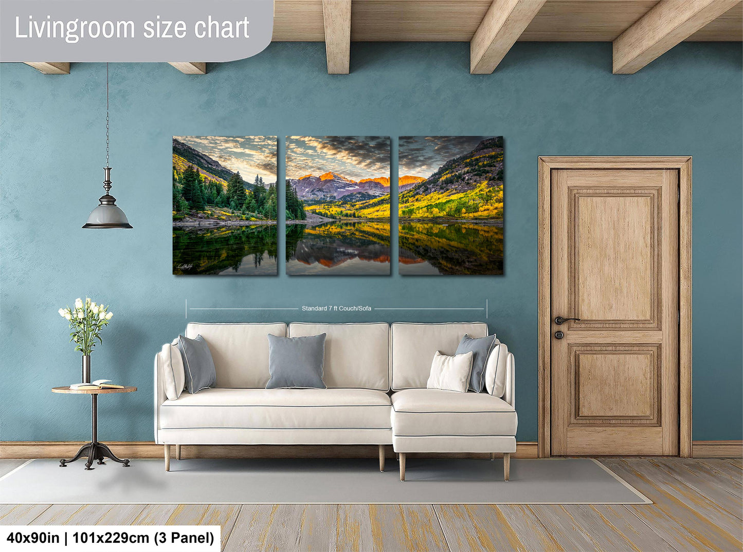 The image is a living room with a large, three-panel landscape painting hanging on the wall. The painting depicts a scenic mountain landscape with a lake and trees. The room has a white sofa and a wooden door, creating a cozy and inviting atmosphere.