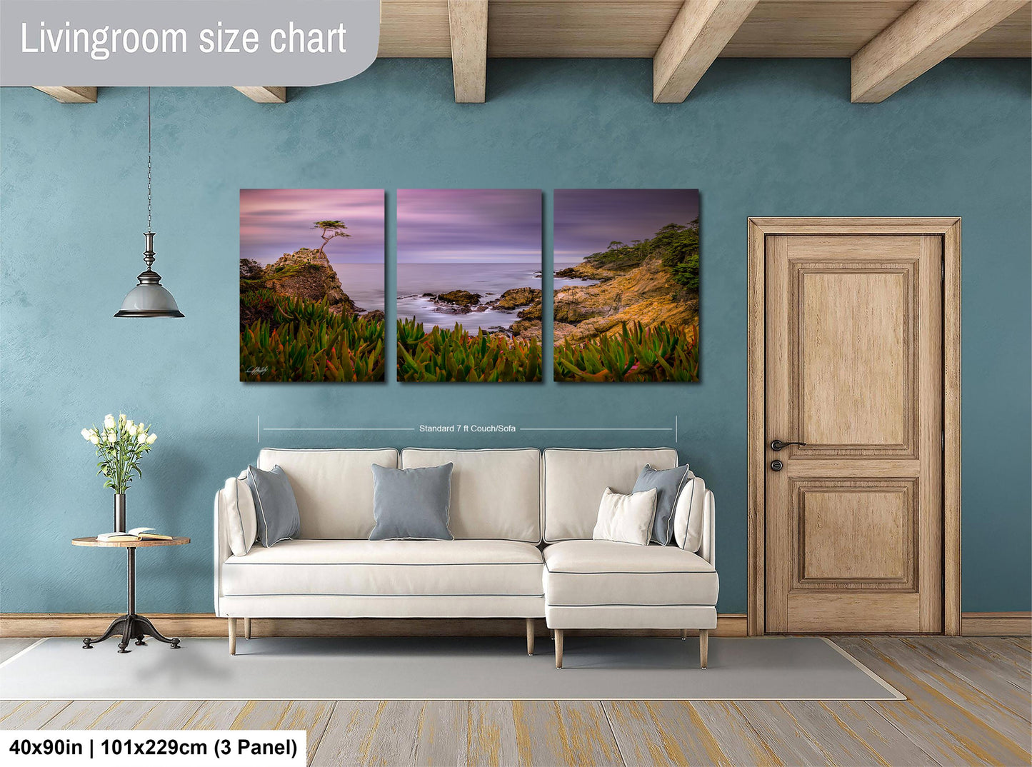 The image is a living room with a large, three-panel landscape painting hanging on the wall. The painting depicts a serene coastal scene with a tree, grass, and rocks. The room has a white sofa and a wooden door, creating a cozy and inviting atmosphere.