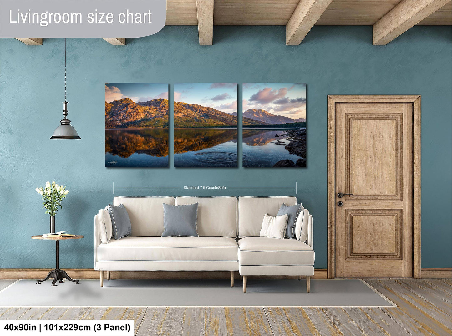 The image is a living room with a large wall art piece depicting a serene landscape with mountains and a lake. The art piece is divided into three panels, each showcasing different aspects of the scene. The living room has a white sofa and a wooden door, creating a cozy and inviting atmosphere.