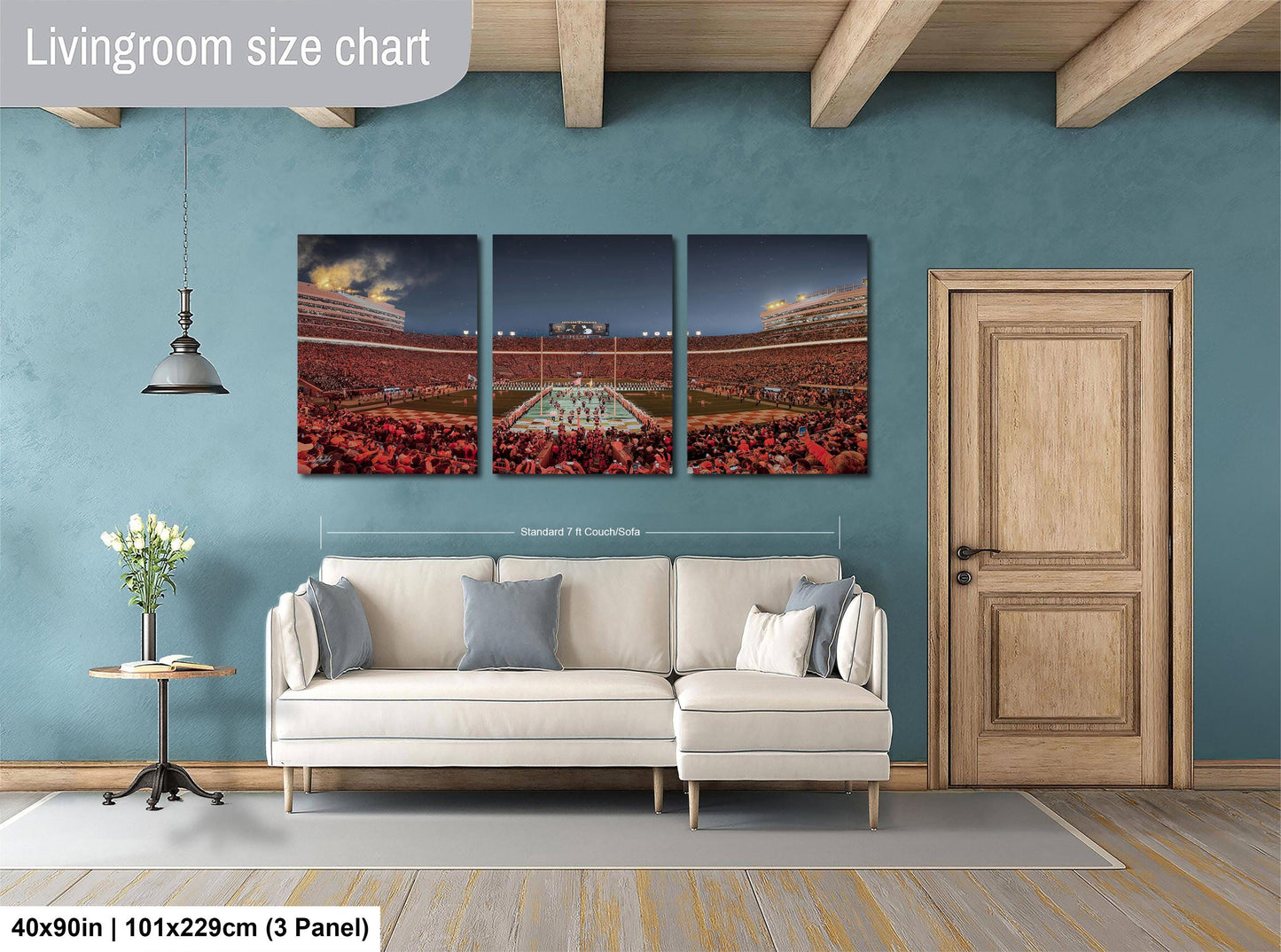 The image is a living room with a large wall art depicting a stadium scene. The wall art is divided into three panels, each showing different parts of the stadium. The living room has a white sofa and a wooden door. The wall art is approximately 40 inches wide and 101.29 cm tall, with a 3-panel arrangement.