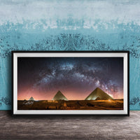 a framed photograph of the pyramids of Giza at night, with the stars visible in the sky above the ancient structures.