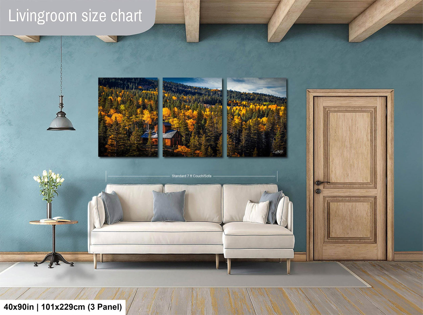 The image is a living room with a large, three-panel landscape painting hanging on the wall. The painting depicts a forest scene with trees displaying autumn colors. The room has a white sofa, a wooden door, and a small table with a vase of flowers. The painting is approximately 40 inches wide and 101.29 cm tall, with a 3-panel layout.