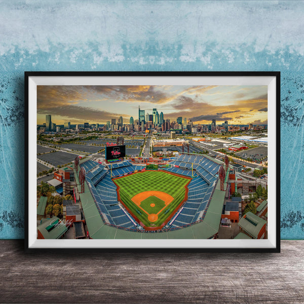 The image is a framed photograph of a baseball stadium in a city, with the city skyline visible in the background.