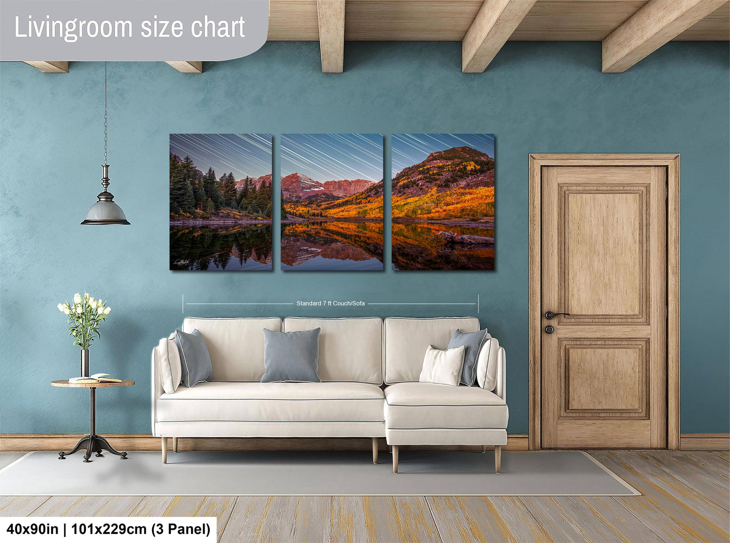 The image is a living room with a large, three-panel landscape painting hanging on the wall. The painting depicts a scenic mountain landscape with a lake and trees. The room has a white sofa and a wooden door, creating a cozy and inviting atmosphere.
