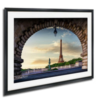 a framed photograph of the Eiffel Tower in Paris, France, with a stone archway framing the view of the iconic landmark.