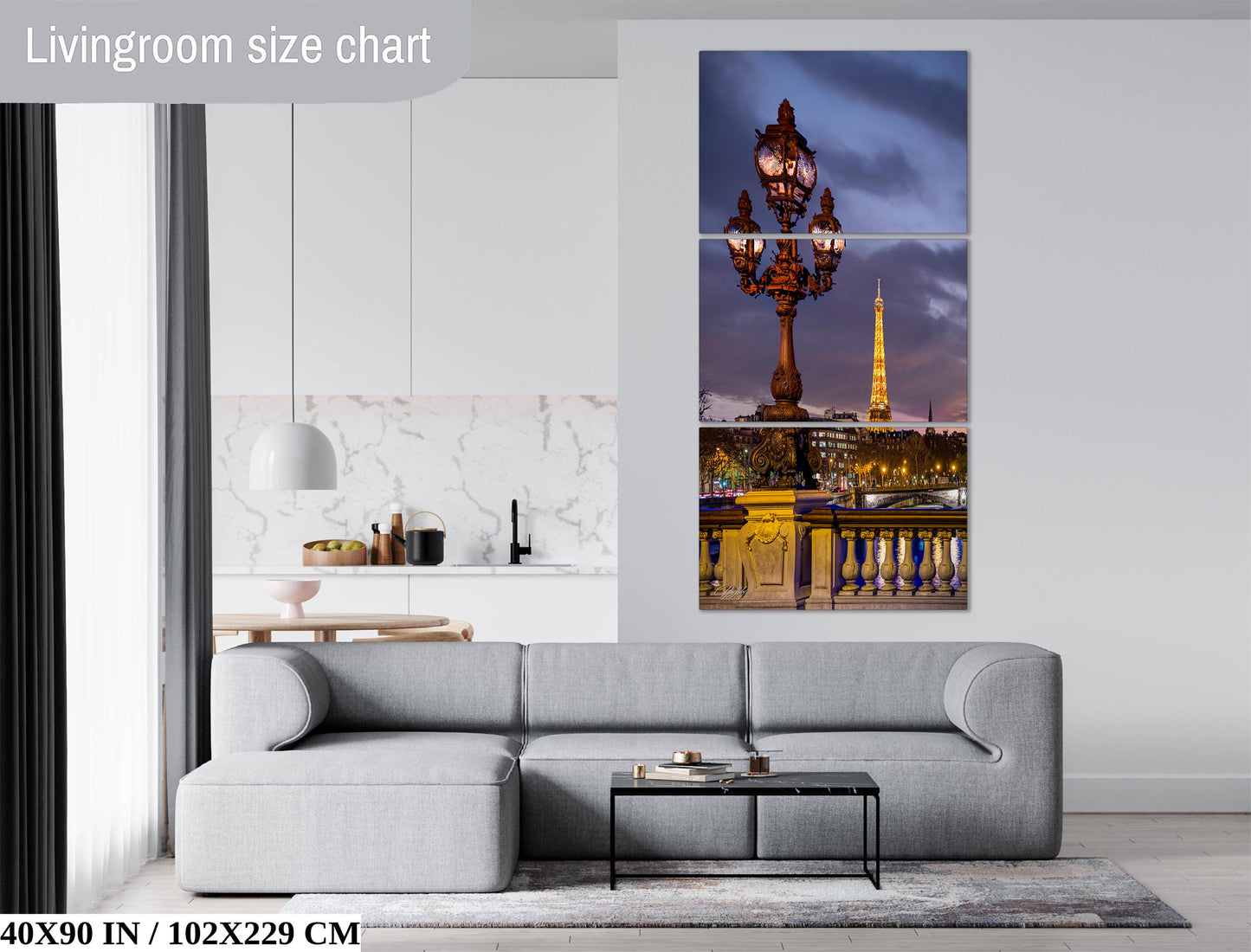 The image is a living room with a gray sofa and a coffee table. Above the sofa, there is a large wall art depicting the Eiffel Tower and the Paris skyline at night.
