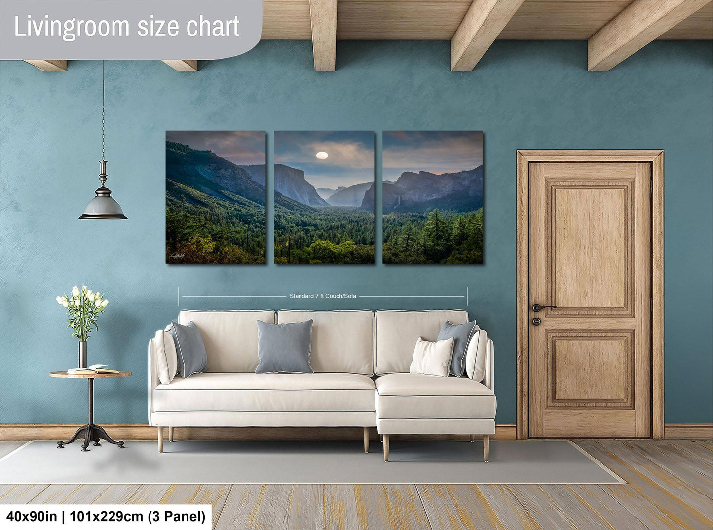 The image is a living room with a large, three-panel landscape painting hanging on the wall. The painting depicts a scenic mountain landscape with a full moon in the sky. The room has a white sofa and a wooden door, creating a cozy and inviting atmosphere.