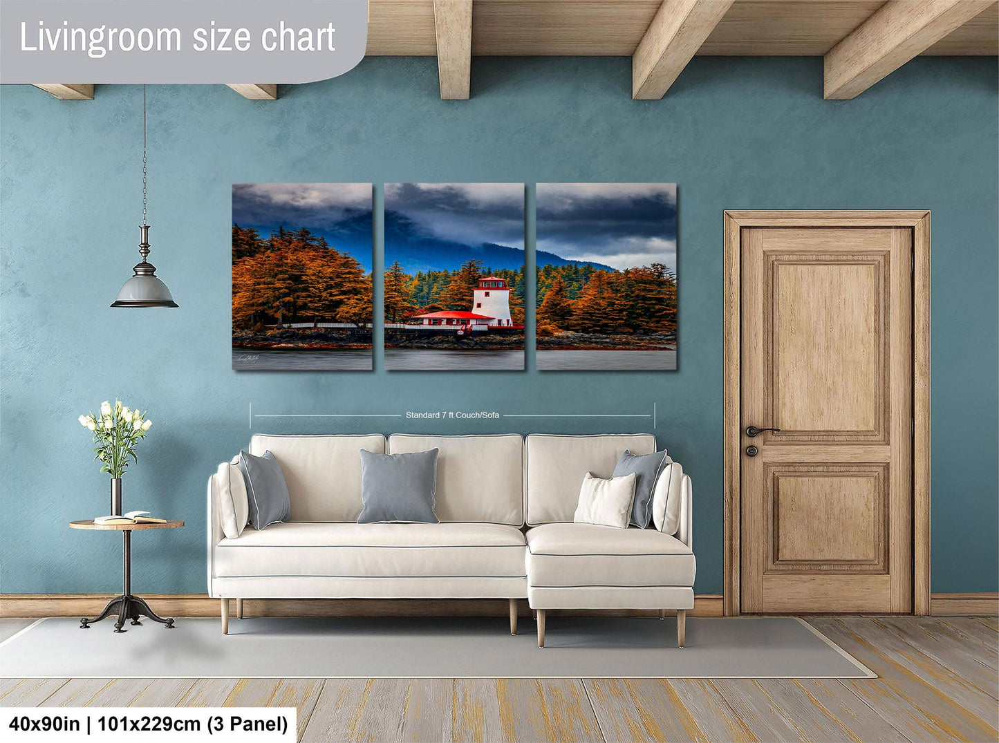 The image is a living room with a white sofa and a wooden door. Above the sofa, there is a large living room size chart that provides dimensions for the artwork displayed on the wall. The artwork is a triptych depicting a scenic landscape with a red building and trees in the background.